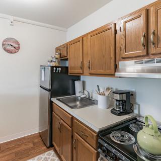 A compact kitchen with wooden cabinets, a refrigerator, stove, and countertop appliances.