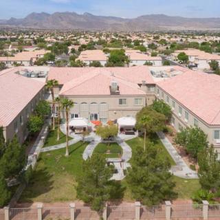Aerial view of a residential neighborhood with gardens and mountain backdrop.