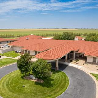 Aerial view of a suburban residential building with a circular driveway and landscaped surroundings.