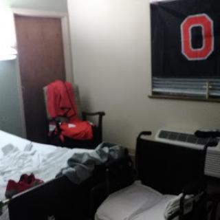 A cozy but cluttered bedroom featuring a flag and messy bedding.