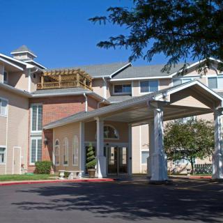 A residential building with a prominent entrance and covered driveway under a clear blue sky.