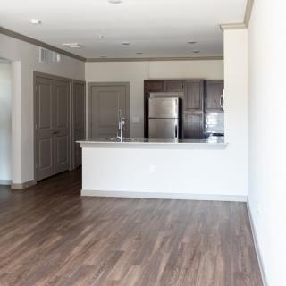 Modern apartment with an open kitchen and living area featuring hardwood floors and stainless steel appliances.