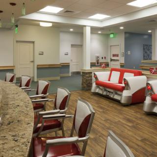 A well-lit, modern waiting area with red and white couches and chairs arranged neatly on a wood floor.