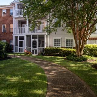An apartment building with a well-maintained pathway and lush landscaping.