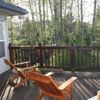 A peaceful deck with wooden chairs overlooking a lush forest.