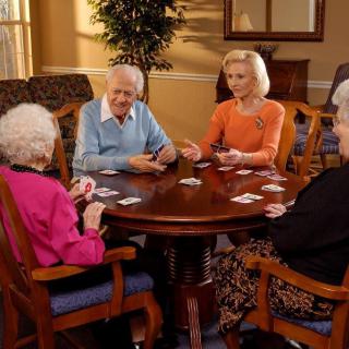 A group of elderly individuals enjoying a card game together indoors.