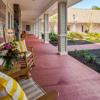 A welcoming porch with a rocking chair and vibrant flowers, perfect for relaxing outdoors.