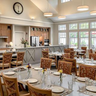 A well-lit dining room with neatly arranged tables and chairs, featuring large windows and a modern interior design.