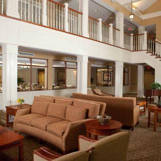 A spacious lobby with comfortable seating and a staircase leading to an upper level.