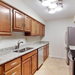A modern kitchen with wooden cabinets, granite countertops, and stainless steel appliances.
