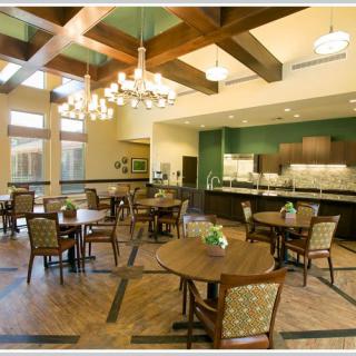 A well-lit dining area with wooden tables and chairs, featuring chandeliers and modern interior design.