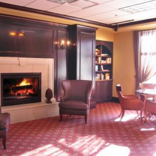 A cozy room with a fireplace, armchairs, and a table, creating a warm atmosphere.