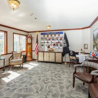 A well-lit office space featuring comfortable chairs, a grandfather clock, and wall decorations.