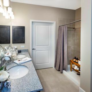 A modern bathroom featuring double sinks, a large mirror, and a shower with a curtain.