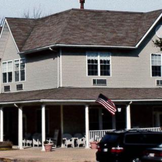 A suburban two-story house with a porch and an American flag.