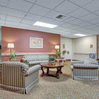 A cozy waiting room with sofas, chairs, and a central coffee table.