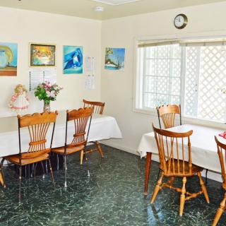 A cozy dining room with two tables, chairs, wall art, and a window letting in natural light.