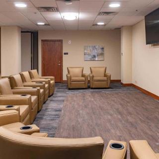 A modern waiting room with comfortable armchairs and a television.