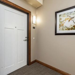 A hallway featuring a white door and framed artwork on the wall.