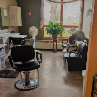 A cozy hair salon with chairs, mirrors, and a large window letting in natural light.