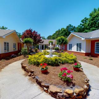 A serene courtyard with a central fountain surrounded by landscaped gardens and pathways between buildings.