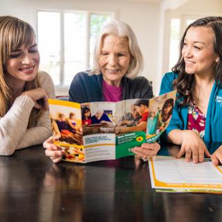 Three women enjoying a moment together as they read and discuss a brochure.