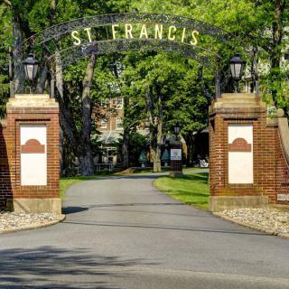 Entrance to St. Francis campus with brick pillars and an archway.