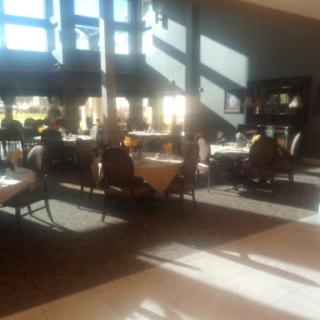 A well-lit dining area showcasing elegant tables and chairs, enhanced by striking sunlight patterns.