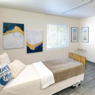 A modern and minimalist bedroom featuring abstract artwork and a cozy bed.