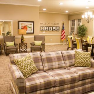 A cozy living room with a plaid sofa, elegant chandelier, and American flag decor.