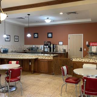 A vintage-style cafe with red and white decor, featuring a coffee station and seating area.