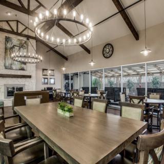 A spacious and modern dining room with a large wooden table, elegant chandeliers, and high ceilings.