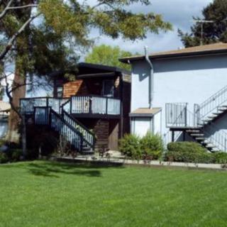 A two-story residential building with exterior stairs and a well-maintained lawn.