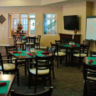 A cozy dining area with neatly arranged tables and chairs, a television, and a whiteboard.