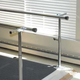 A ballet barre in front of window blinds in a dance studio.