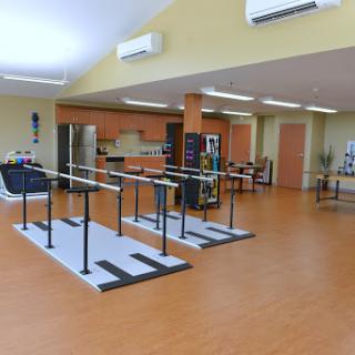 A spacious therapy room equipped with ballet bars and exercise equipment, designed for rehabilitation activities.