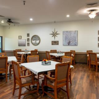 A cozy dining room with wooden tables and chairs, adorned with wall decor and a warm ambiance.