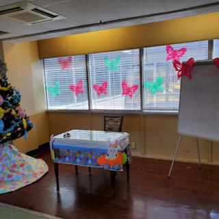A decorated workspace featuring a table, whiteboard, and colorful butterfly decorations by the windows.
