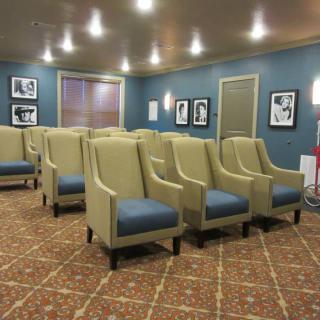 An empty movie theater with comfortable seating and framed pictures on the walls.