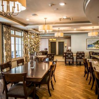 An elegant dining room with wooden flooring, sophisticated lighting, and arranged tables and chairs.