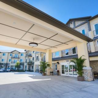 A modern building entrance with a covered driveway and clear blue sky.