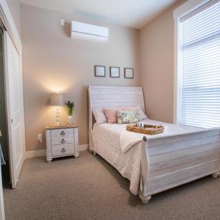 A cozy and minimalist bedroom with a neatly made bed, nightstand, lamp, and window blinds.