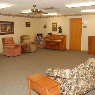 A cozy living room with various pieces of furniture including a couch, chairs, and a piano.