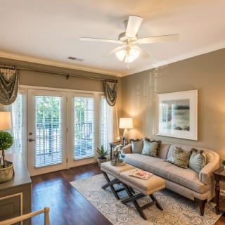 A cozy and elegantly furnished living room with large windows, a comfortable couch, and decorative elements.