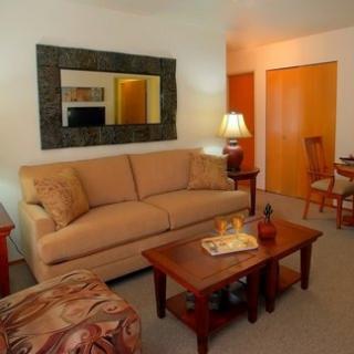 A cozy living room featuring a beige sofa, wooden coffee table, and warm lighting.