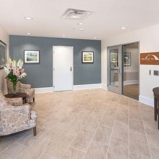 A modern lobby area with comfortable chairs, artwork on the walls, and a vase of flowers.