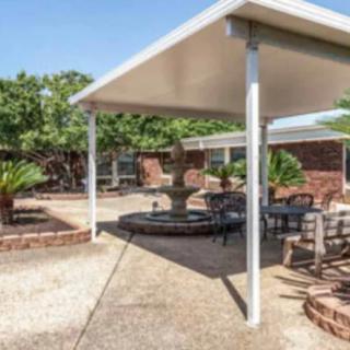 A spacious outdoor patio featuring a central fountain, surrounded by seating areas and greenery.