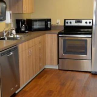 A modern kitchen with stainless steel appliances and wood cabinetry.