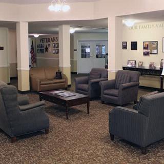 A spacious lobby seating area with comfortable chairs, a sofa, and a coffee table on a carpeted floor.