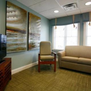 A cozy living room with a sofa, chair, television, and large artwork on the walls.